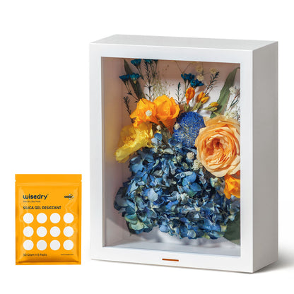 A clear, airtight flower shadow box with dried roses inside, featuring a hidden desiccant compartment and a humidity indicator.